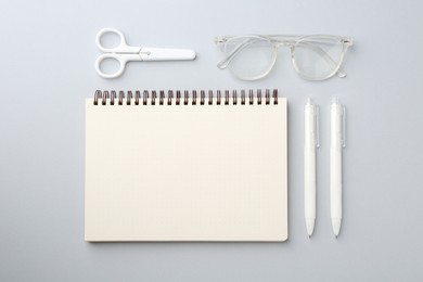 Photo of Notebook, scissors, pens and glasses on gray background, flat lay