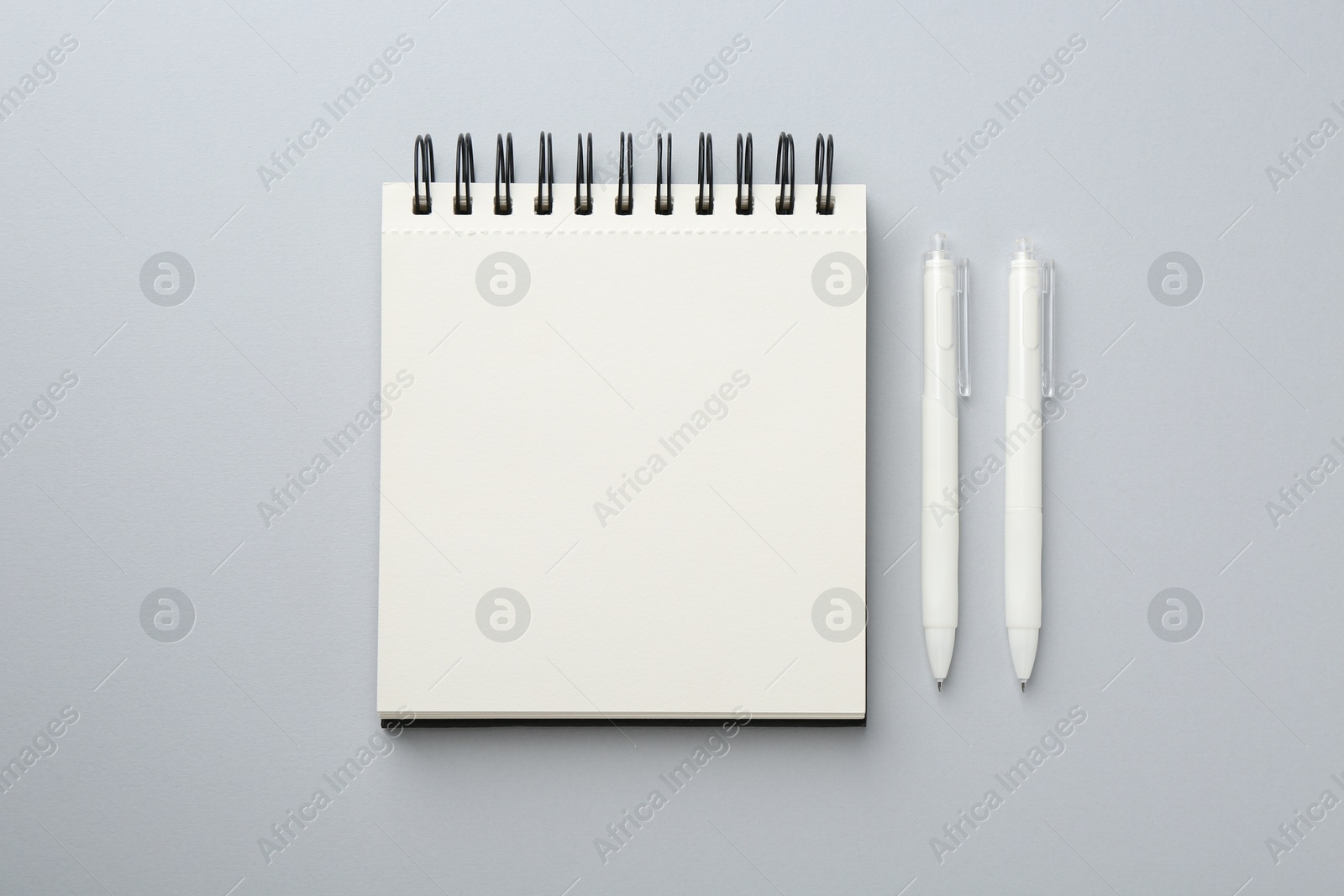 Photo of Notebook and pens on gray background, flat lay