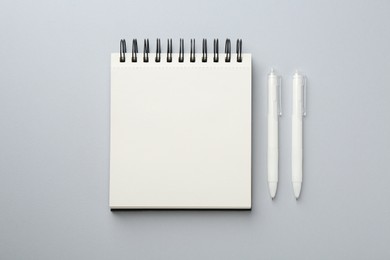 Photo of Notebook and pens on gray background, flat lay