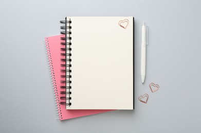 Photo of Notebooks, pen and paper clips on gray background, flat lay
