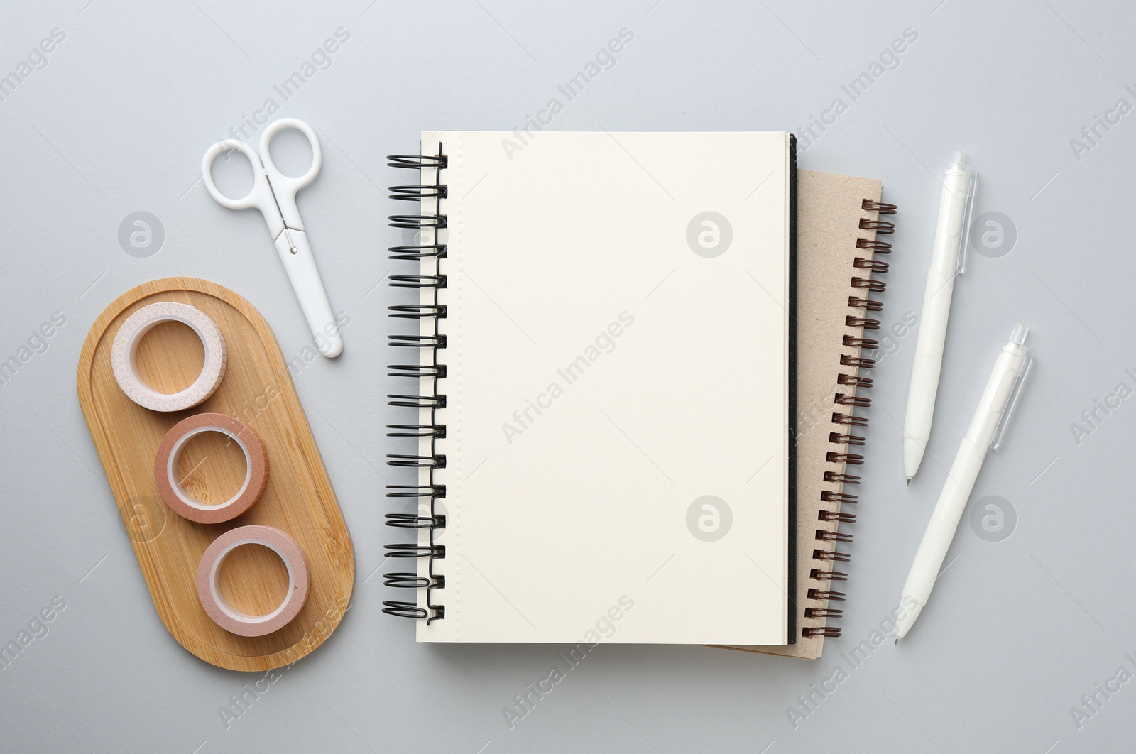 Photo of Notebooks, decorative craft tapes, scissors and pens on gray background, flat lay