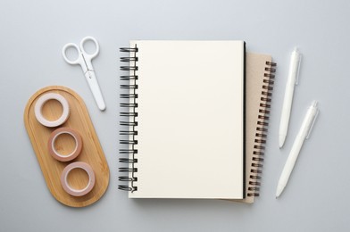 Photo of Notebooks, decorative craft tapes, scissors and pens on gray background, flat lay