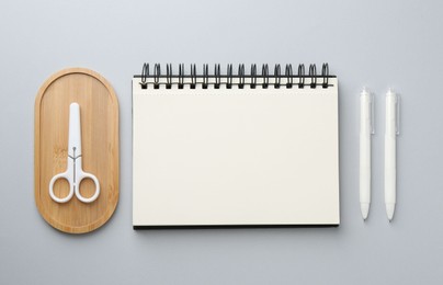 Photo of Notebook, scissors and pens on gray background, flat lay