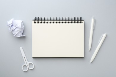 Photo of Notebook, scissors, crumpled paper and pens on gray background, flat lay