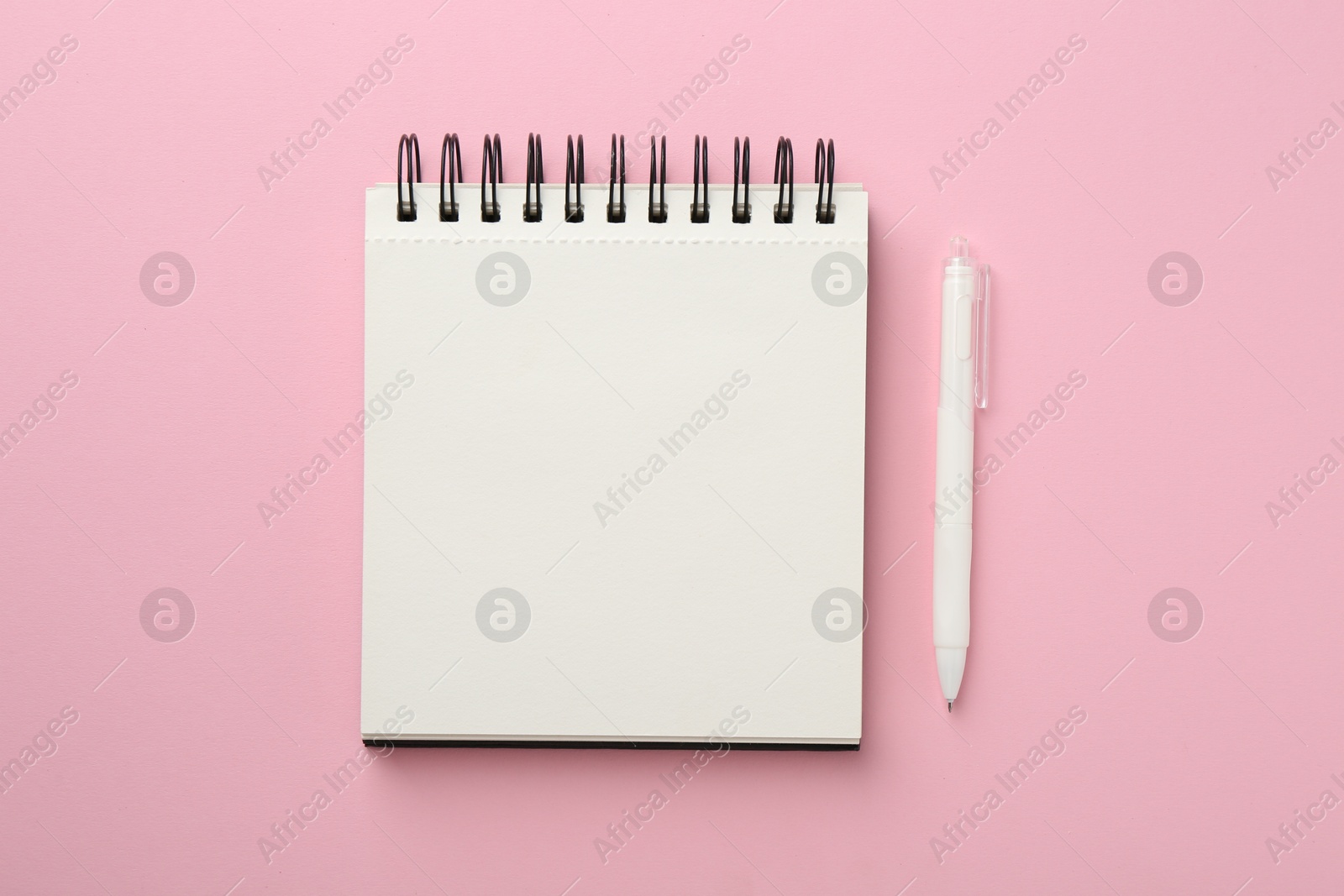 Photo of Notebook and pen on pink background, flat lay