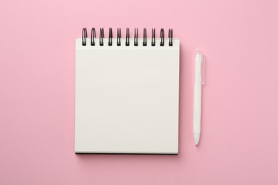 Photo of Notebook and pen on pink background, flat lay