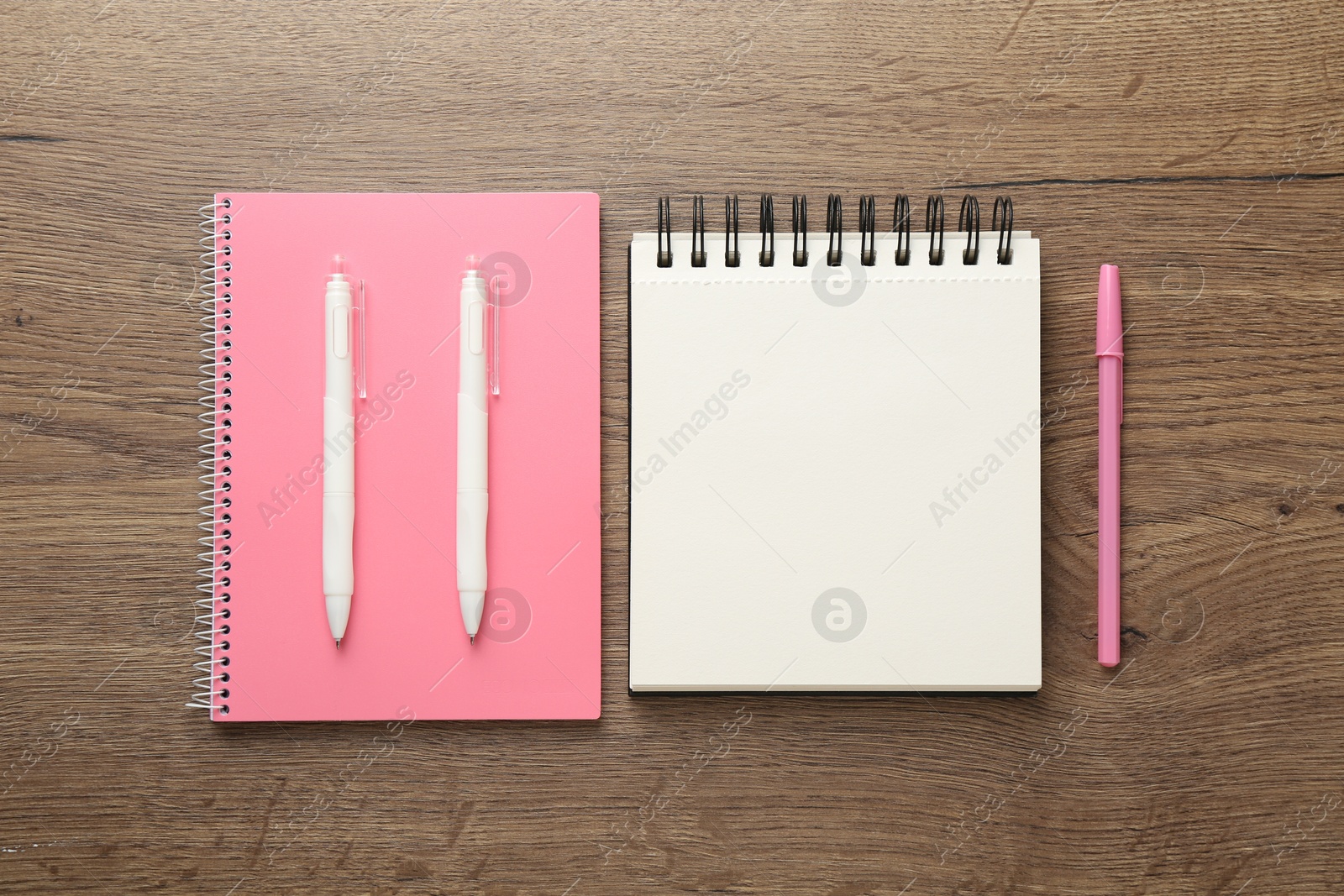 Photo of Notebooks and pens on wooden table, flat lay