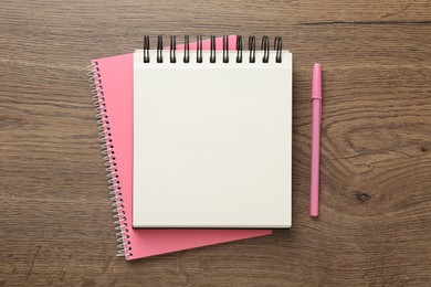 Photo of Notebooks and pen on wooden table, flat lay