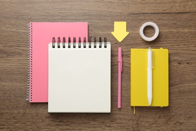 Photo of Notebooks, pens, sticky notes and decorative craft tape on wooden table, flat lay
