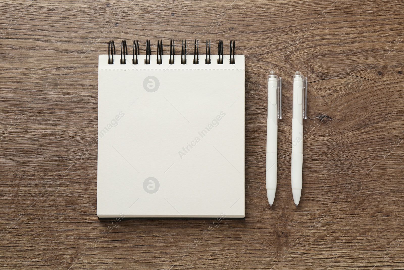 Photo of Notebook and pens on wooden table, flat lay