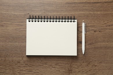 Photo of Notebook and pen on wooden table, flat lay