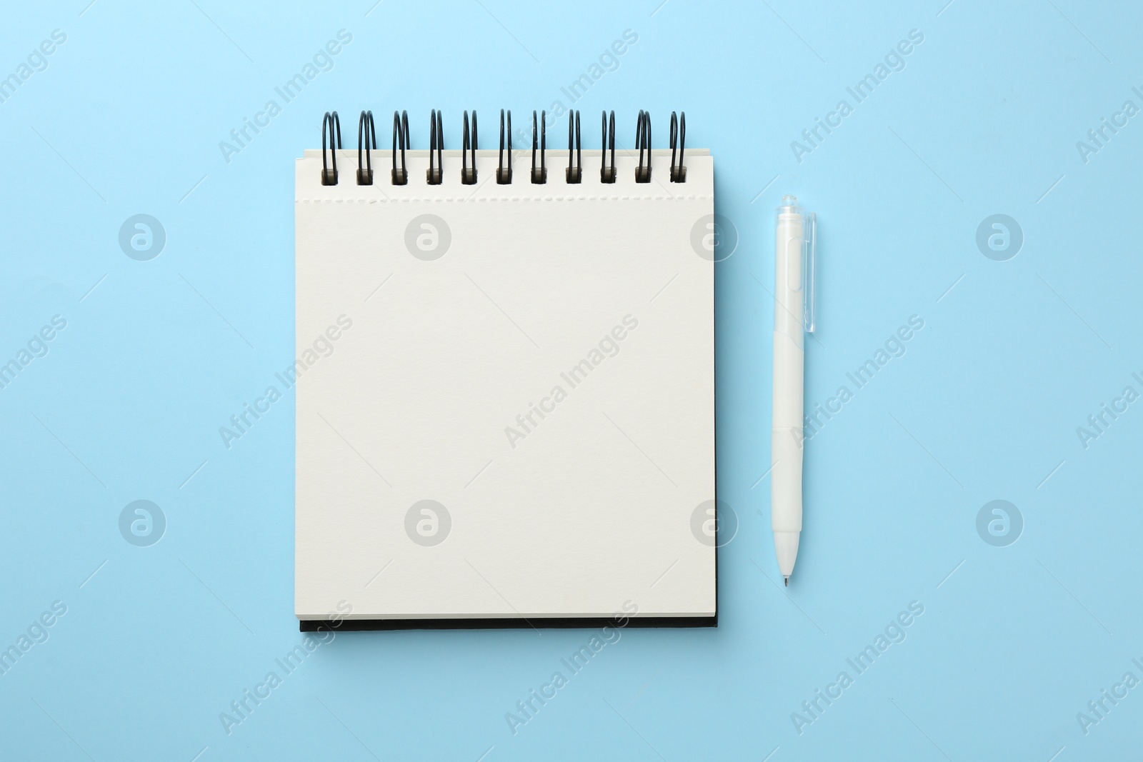Photo of Notebook and pen a on light blue background, flat lay