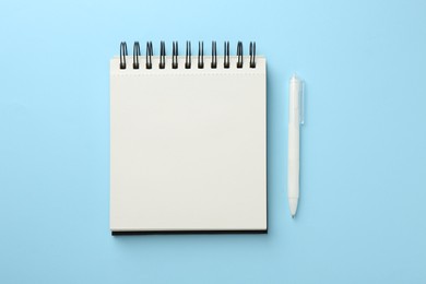 Photo of Notebook and pen a on light blue background, flat lay