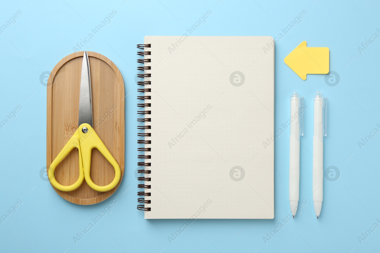 Notebook, scissors, pens and sticky notes on light blue background, flat lay Photo of Notebook, scissors, pens and sticky notes on light blue background, flat lay