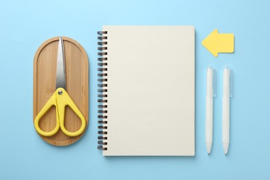 Photo of Notebook, scissors, pens and sticky notes on light blue background, flat lay