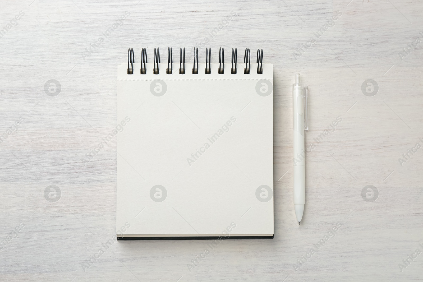 Photo of Notebook and pen on light wooden table, flat lay