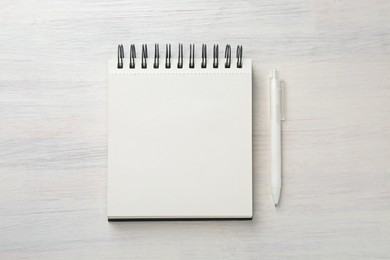 Photo of Notebook and pen on light wooden table, flat lay