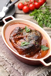 Photo of Traditional ossobuco dish with beef steak and sauce served on wooden table, closeup