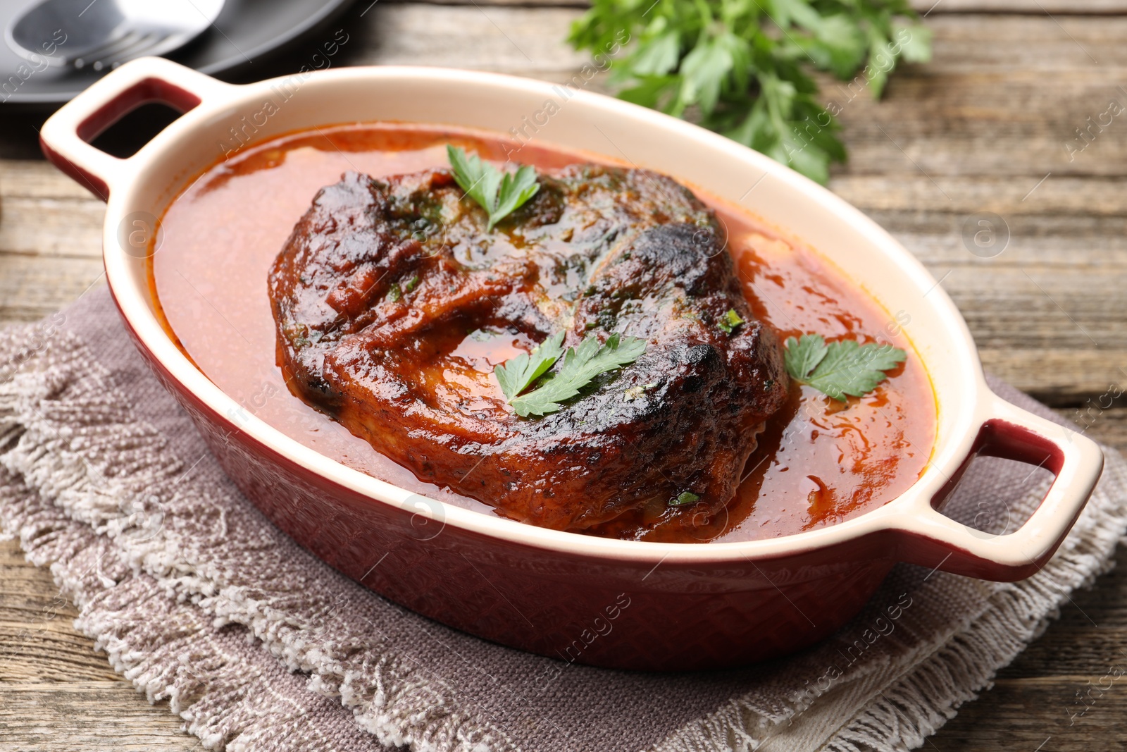 Traditional ossobuco dish with beef steak and sauce on wooden table, closeup Photo of Traditional ossobuco dish with beef steak and sauce on wooden table, closeup