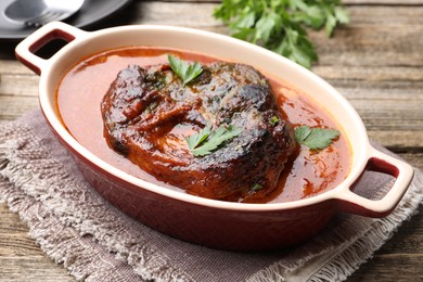 Photo of Traditional ossobuco dish with beef steak and sauce on wooden table, closeup