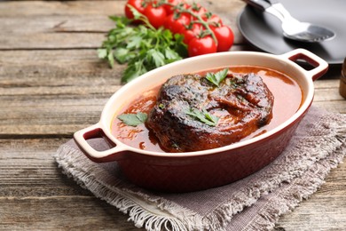 Photo of Traditional ossobuco dish with beef steak and sauce served on wooden table, closeup