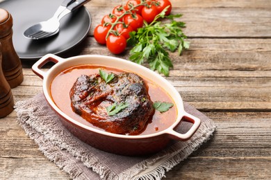 Photo of Traditional ossobuco dish with beef steak and sauce served on wooden table, above view. Space for text