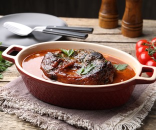 Photo of Traditional ossobuco dish with beef steak and sauce served on wooden table, closeup