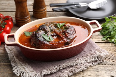 Photo of Traditional ossobuco dish with beef steak and sauce served on wooden table, closeup
