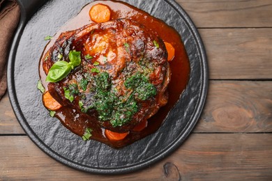 Photo of Traditional ossobuco dish with beef steak and sauce served on wooden table, top view