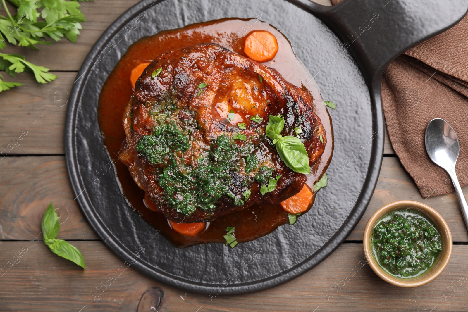 Photo of Traditional ossobuco dish with beef steak and sauce served on wooden table, flat lay