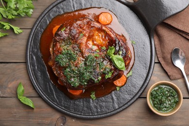 Photo of Traditional ossobuco dish with beef steak and sauce served on wooden table, flat lay