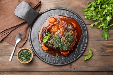 Photo of Traditional ossobuco dish with beef steak and sauce served on wooden table, flat lay