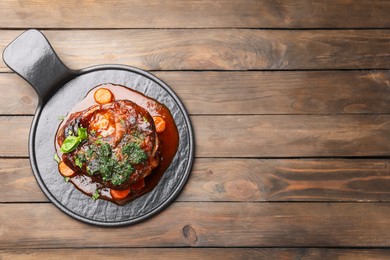 Photo of Traditional ossobuco dish with beef steak and sauce served on wooden table, top view. Space for text