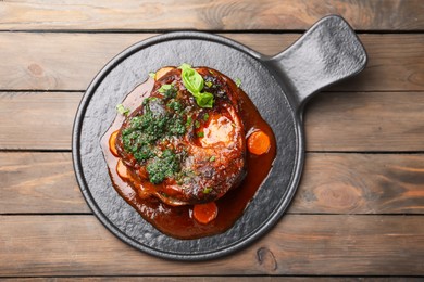 Photo of Traditional ossobuco dish with beef steak and sauce served on wooden table, top view
