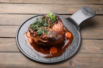 Photo of Traditional ossobuco dish with beef steak and sauce served on wooden table, above view