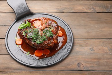 Photo of Traditional ossobuco dish with beef steak and sauce served on wooden table, above view. Space for text