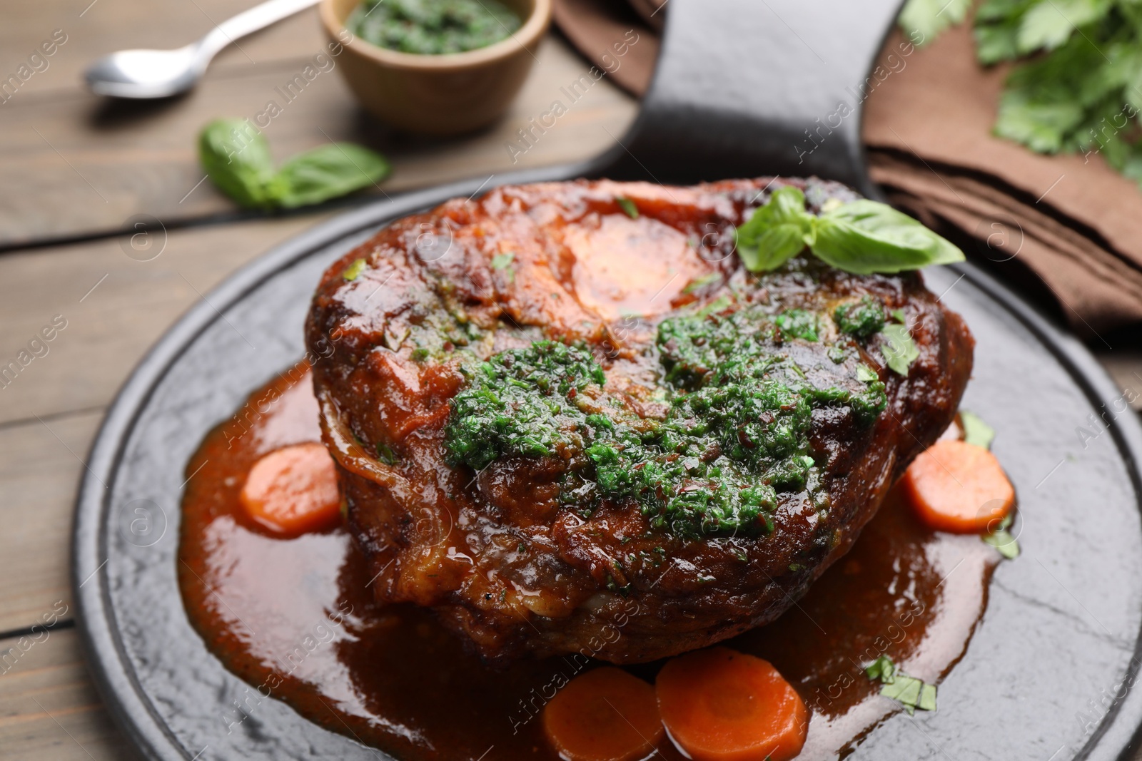 Traditional ossobuco dish with beef steak and sauce served on wooden table, closeup Photo of Traditional ossobuco dish with beef steak and sauce served on wooden table, closeup