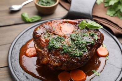 Photo of Traditional ossobuco dish with beef steak and sauce served on wooden table, closeup