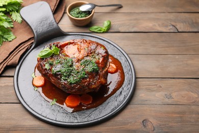 Photo of Traditional ossobuco dish with beef steak and sauce served on wooden table, closeup. Space for text