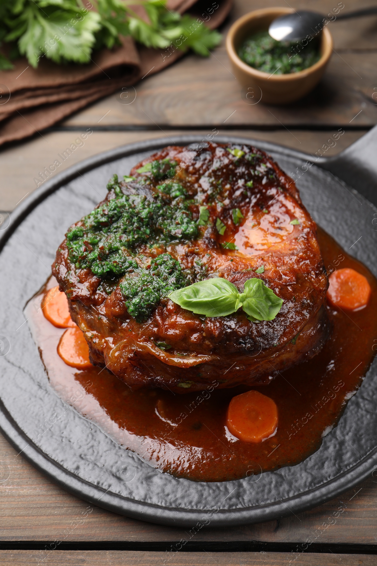 Traditional ossobuco dish with beef steak and sauce served on wooden table, closeup Photo of Traditional ossobuco dish with beef steak and sauce served on wooden table, closeup