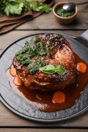 Photo of Traditional ossobuco dish with beef steak and sauce served on wooden table, closeup
