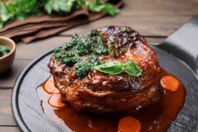 Photo of Traditional ossobuco dish with beef steak and sauce served on wooden table, closeup