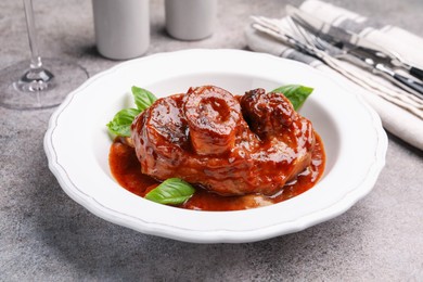 Photo of Traditional ossobuco dish with beef steak served on grey table, closeup