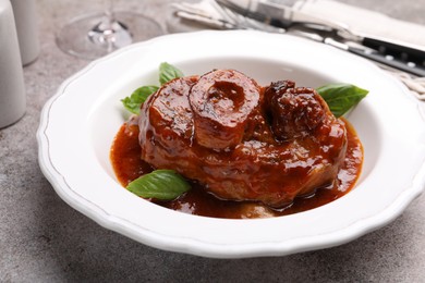 Photo of Traditional ossobuco dish with beef steak served on grey table, closeup