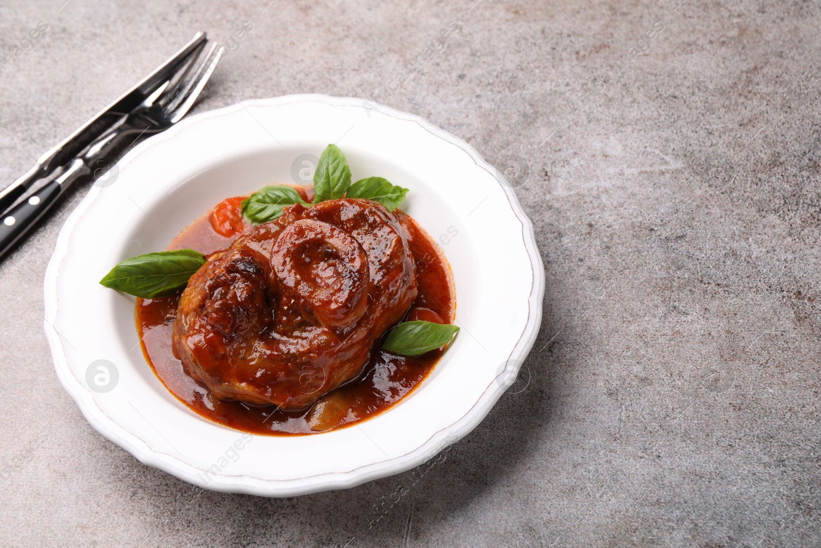 Traditional ossobuco dish with beef steak served on grey table, above view. Space for text Photo of Traditional ossobuco dish with beef steak served on grey table, above view. Space for text