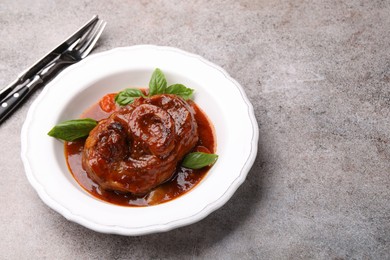 Photo of Traditional ossobuco dish with beef steak served on grey table, above view. Space for text