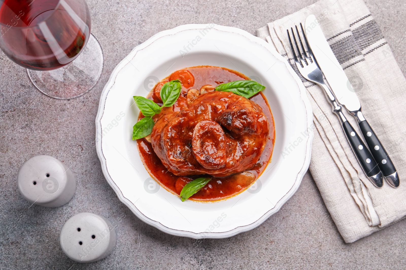 Traditional ossobuco dish with beef steak served on grey table, flat lay Photo of Traditional ossobuco dish with beef steak served on grey table, flat lay