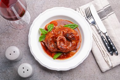 Photo of Traditional ossobuco dish with beef steak served on grey table, flat lay