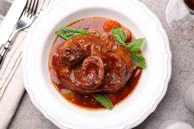 Photo of Traditional ossobuco dish with beef steak served on grey table, flat lay