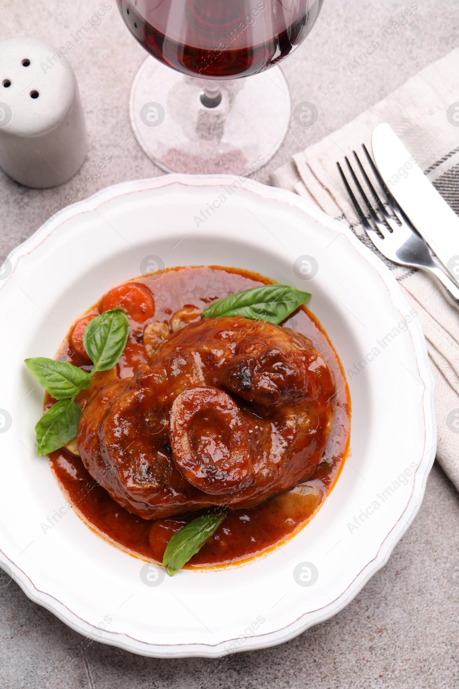 Photo of Traditional ossobuco dish with beef steak served on grey table, flat lay